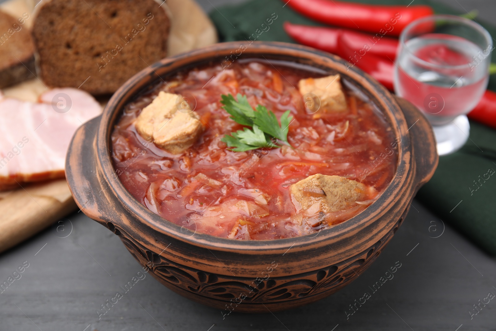 Photo of Tasty borscht in bowl on grey wooden table, closeup