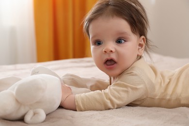 Photo of Cute little baby with toy on bed indoors. Space for text