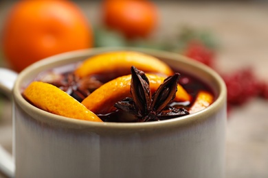 Cup with tasty mulled wine on table, closeup