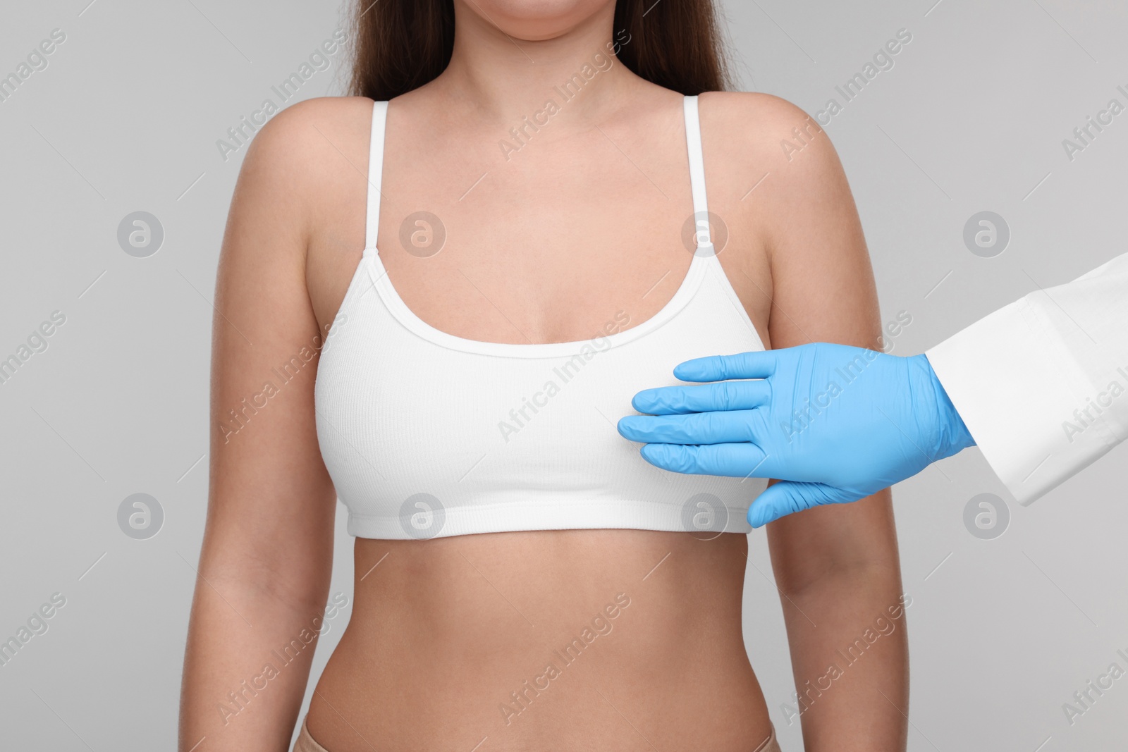 Photo of Mammologist checking woman's breast on light grey background, closeup