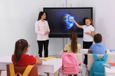 Photo of Teacher and pupil using interactive board in classroom during lesson