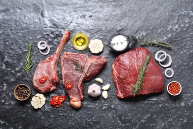 Photo of Fresh raw beef cuts and different spices on grey textured table, flat lay