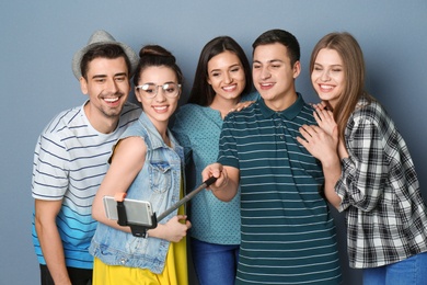 Photo of Young happy friends taking selfie against grey background