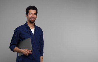 Photo of Happy man with laptop on grey background. Space for text