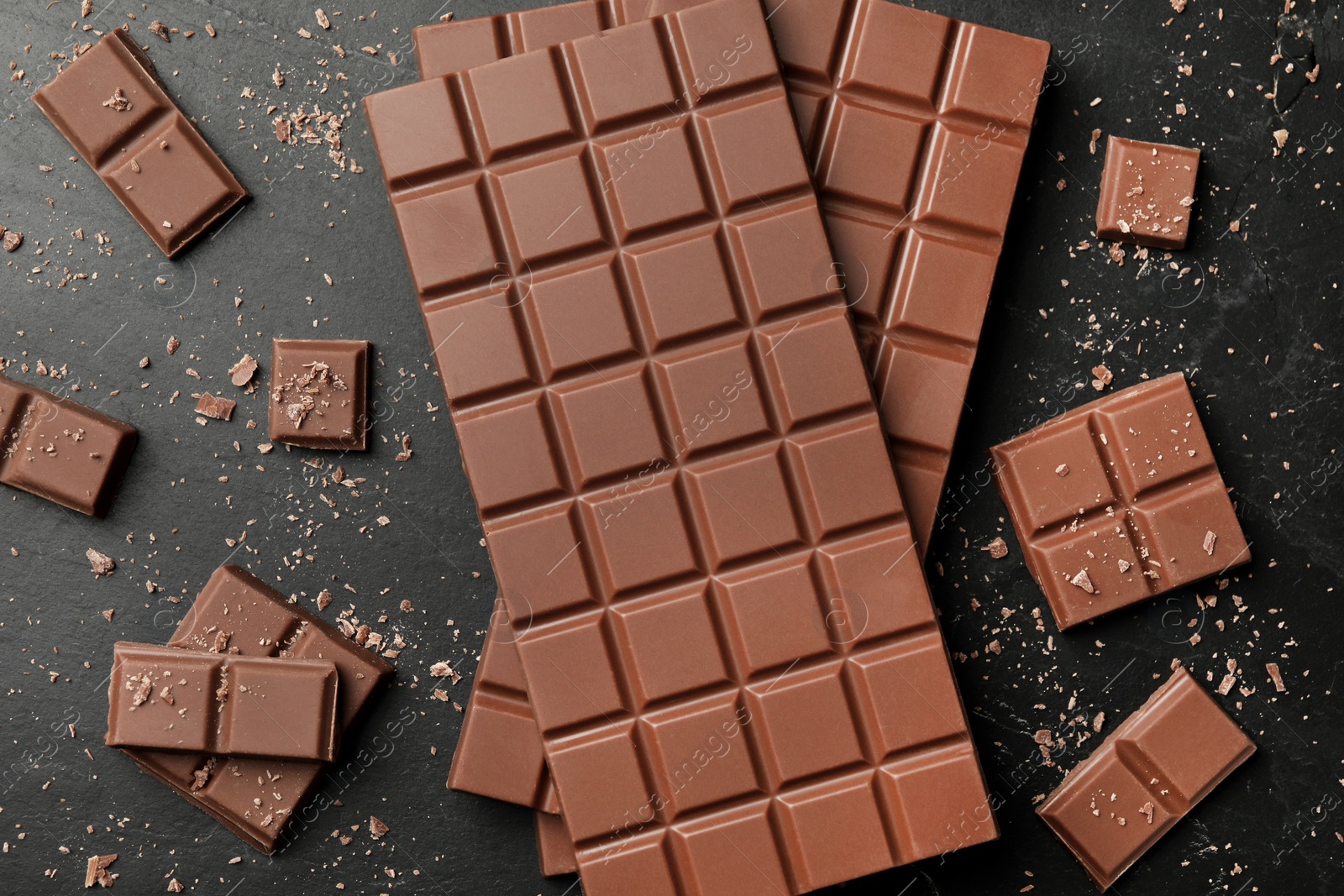 Photo of Pieces of tasty chocolate on grey table, flat lay