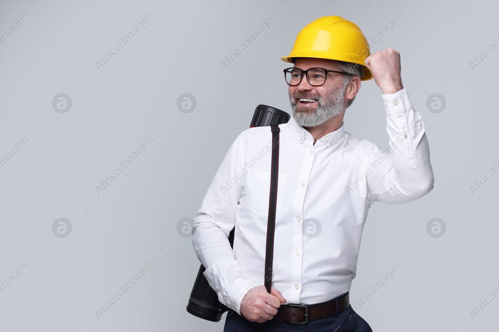 Photo of Architect in hard hat with drawing tube on grey background