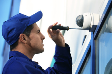 Technician installing CCTV camera on wall outdoors