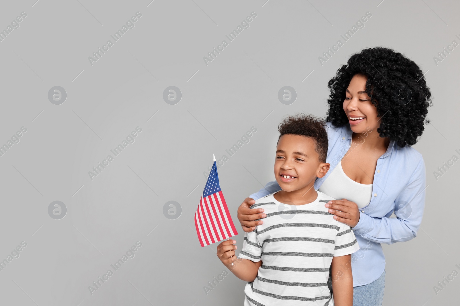 Photo of 4th of July - Independence Day of USA. Happy woman and her son with American flag on light grey background, space for text