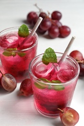 Photo of Delicious grape soda water and berries on white table. Refreshing drink