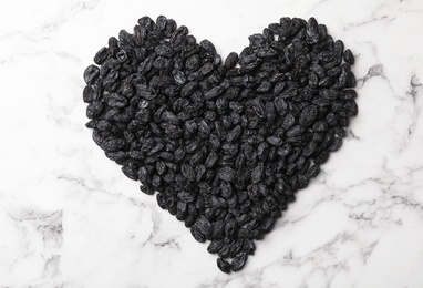 Photo of Heart shape of raisins on marble background. Dried fruit as healthy snack