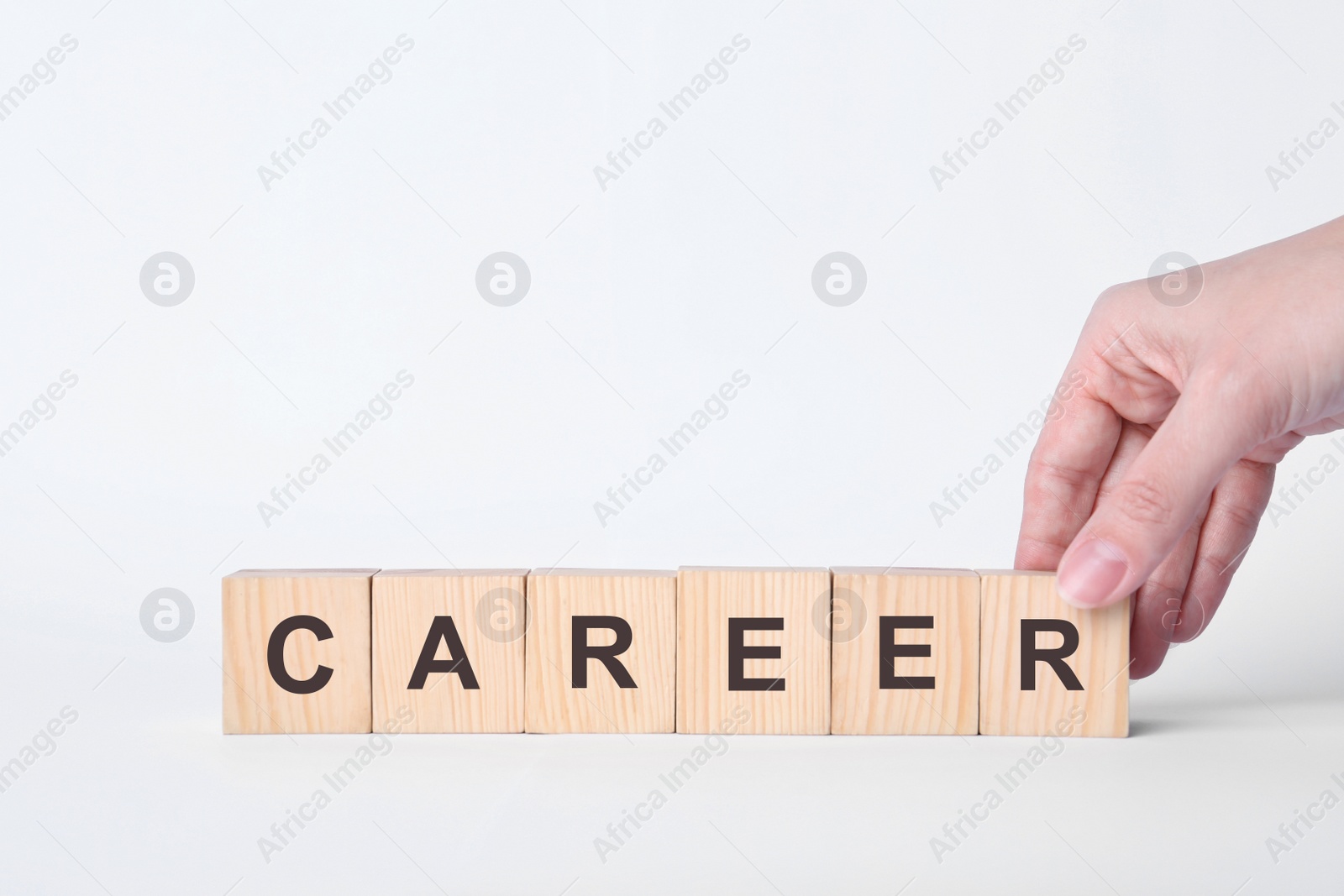 Photo of Woman making word CAREER with wooden cubes on white background, closeup