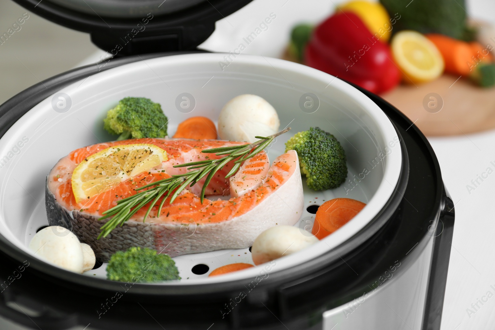 Photo of Salmon steak with garnish in multi cooker on table, closeup