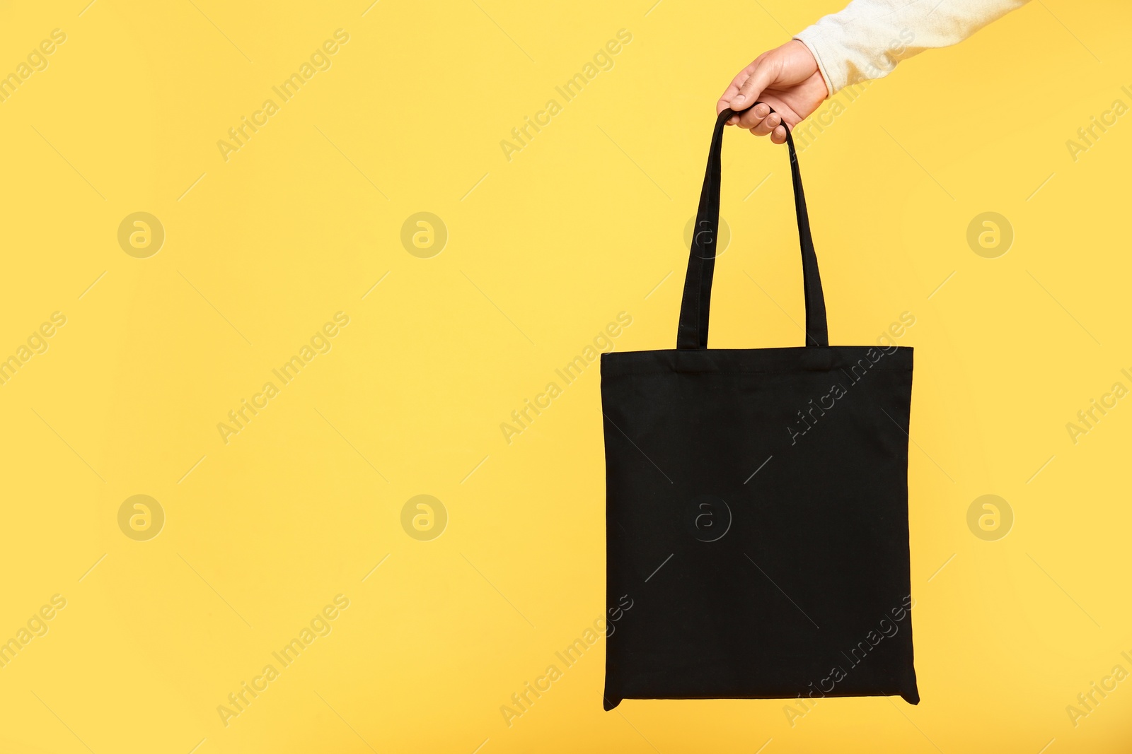 Photo of Young man with eco bag on yellow background, closeup. Space for text