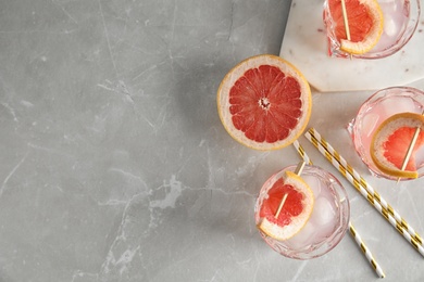 Photo of Flat lay composition with glasses of grapefruit cocktails on grey table. Space for text