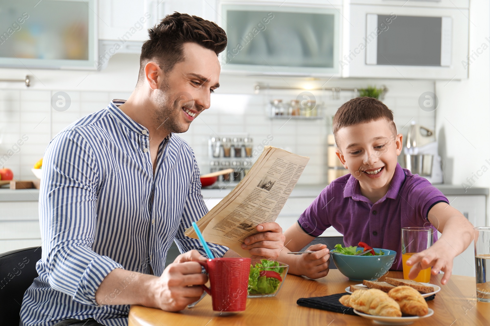 Photo of Dad and son having breakfast together in kitchen