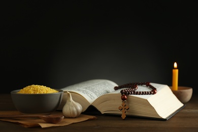 Photo of Fasting meals, Bible, rosary beads and candle on wooden table. Lent season