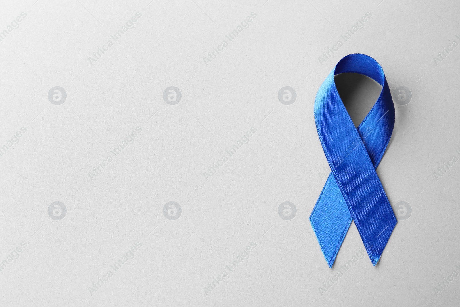 Photo of Blue awareness ribbon on grey background, top view with space for text. Symbol of social and medical issues