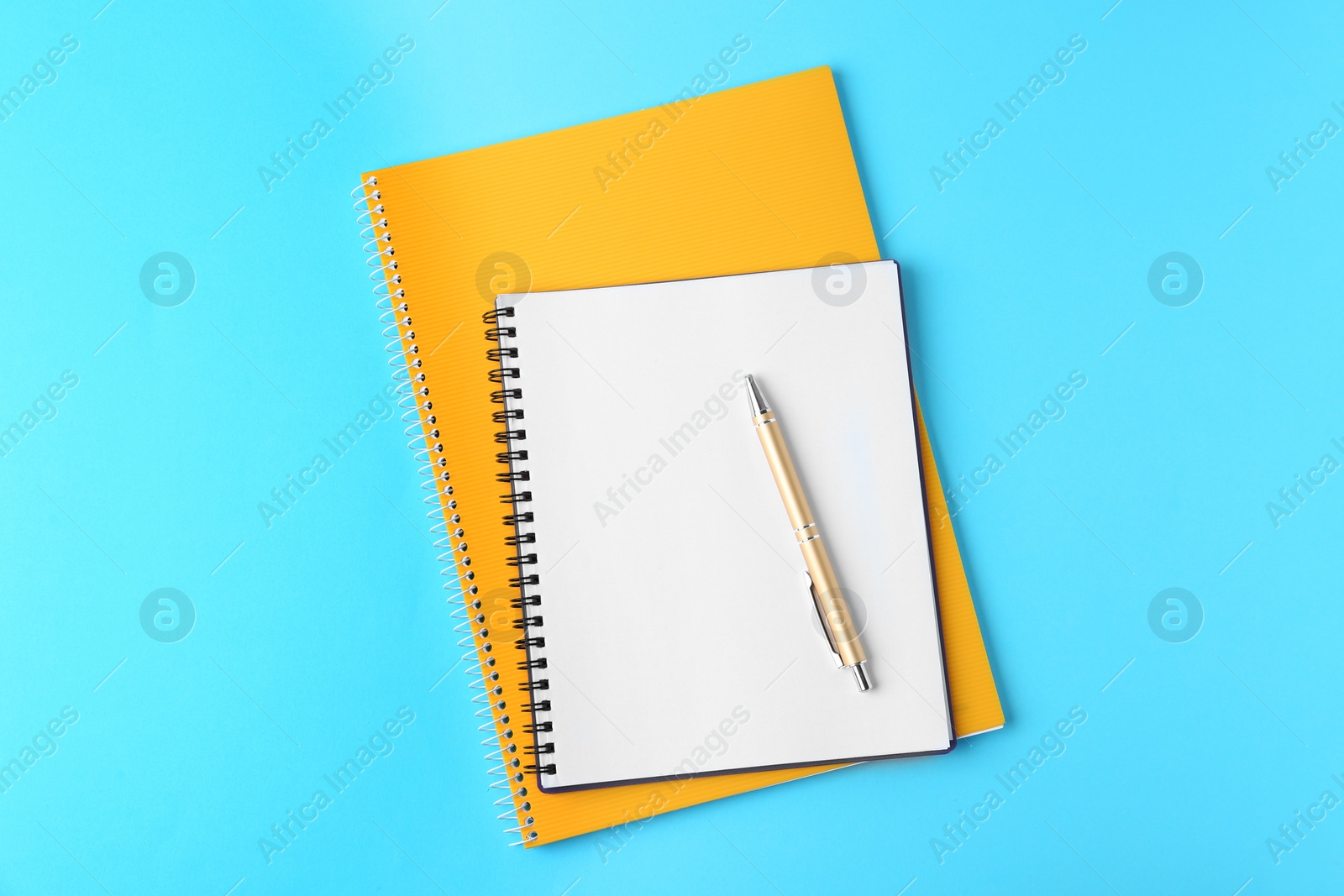 Photo of Notebooks and pen on light blue background, top view