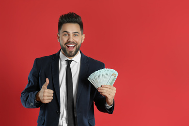 Young man with money on crimson background. Space for text