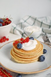 Photo of Tasty pancakes with natural yogurt, blueberries and red currants on marble table