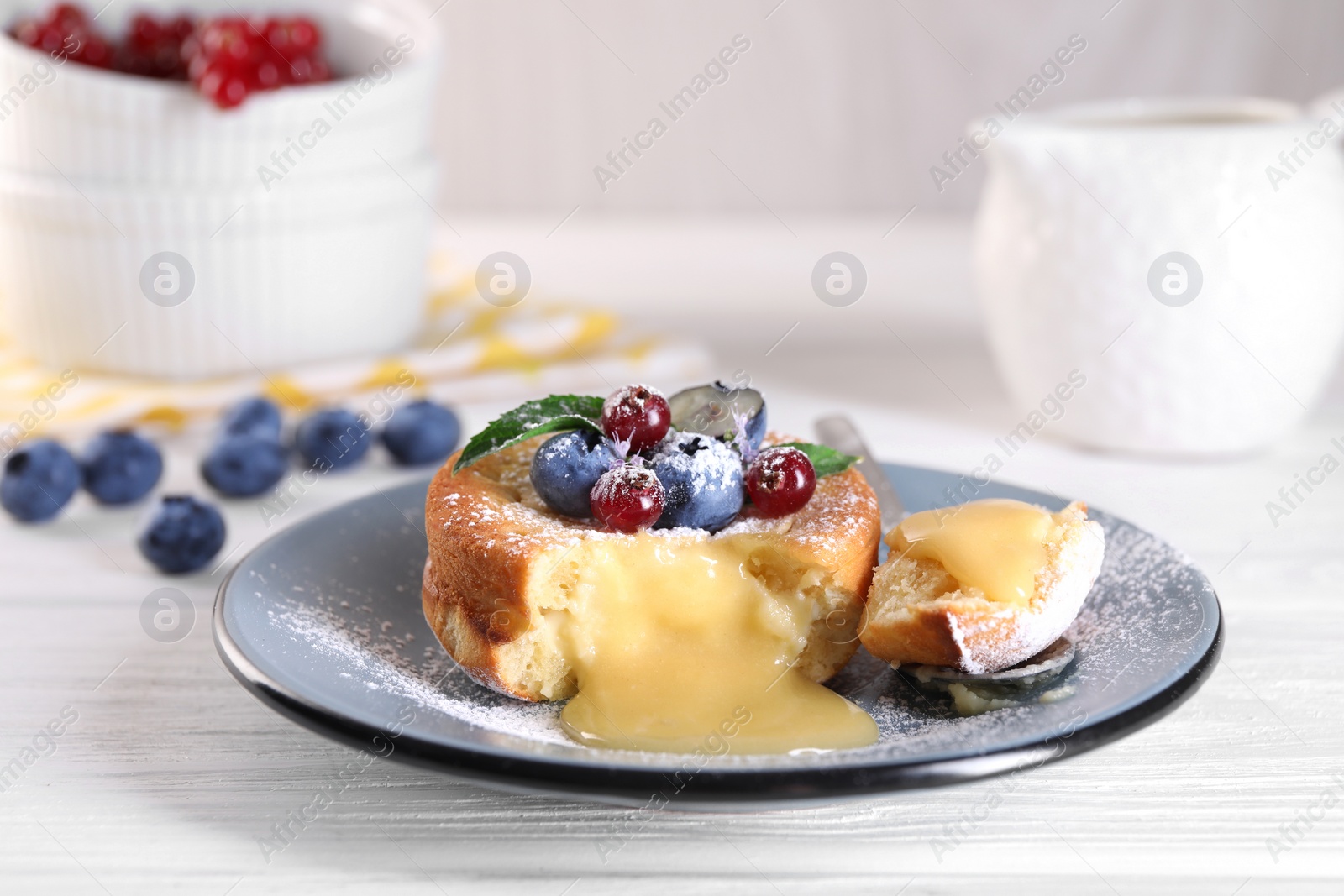 Photo of Tasty vanilla fondant with white chocolate and berries on light wooden table, closeup