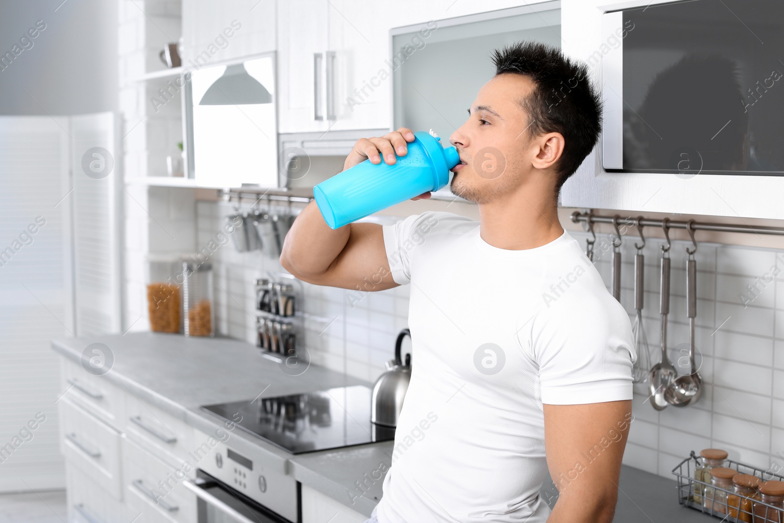 Photo of Young man drinking protein shake in kitchen