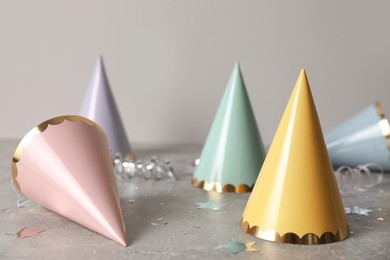 Birthday party hats, serpentine streamers and confetti on grey table