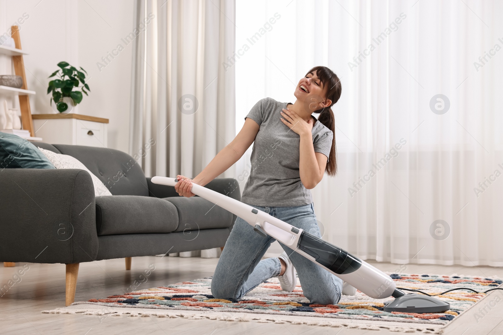 Photo of Happy young housewife having fun while cleaning at home