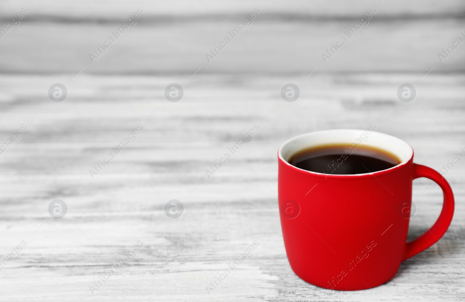 Photo of Red ceramic cup with hot aromatic coffee on table