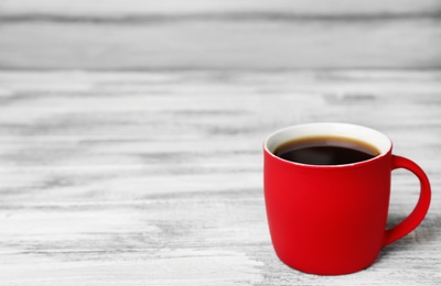 Photo of Red ceramic cup with hot aromatic coffee on table