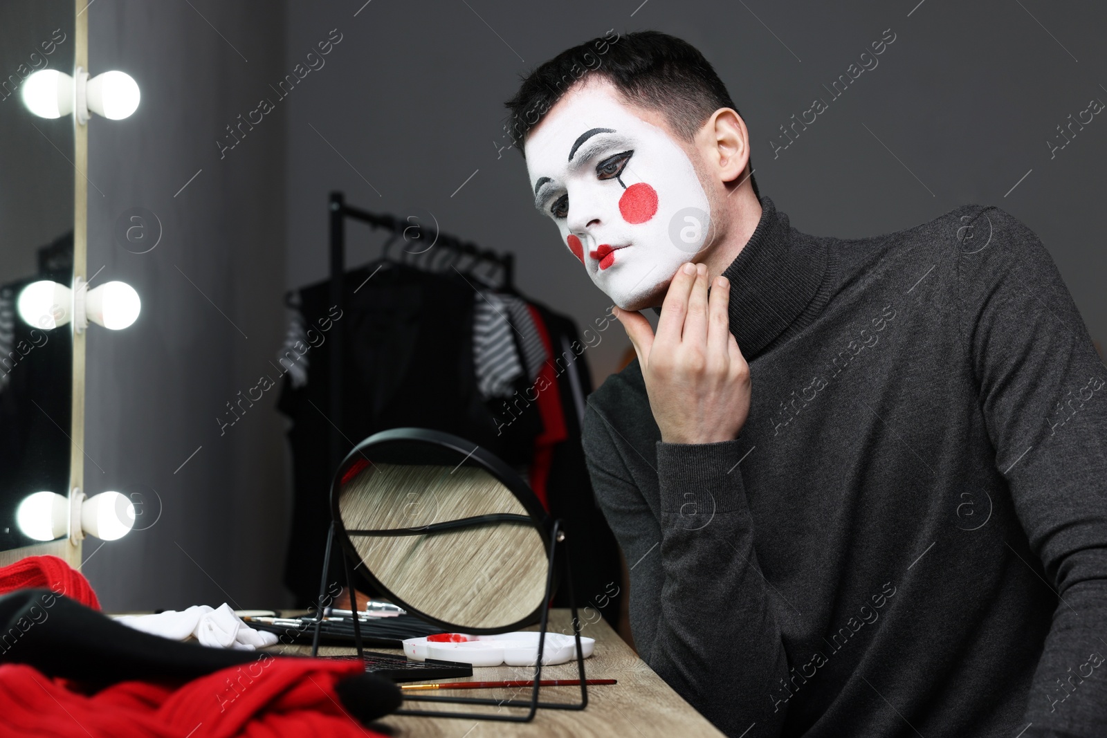 Photo of Mime artist looking at mirror in dressing room