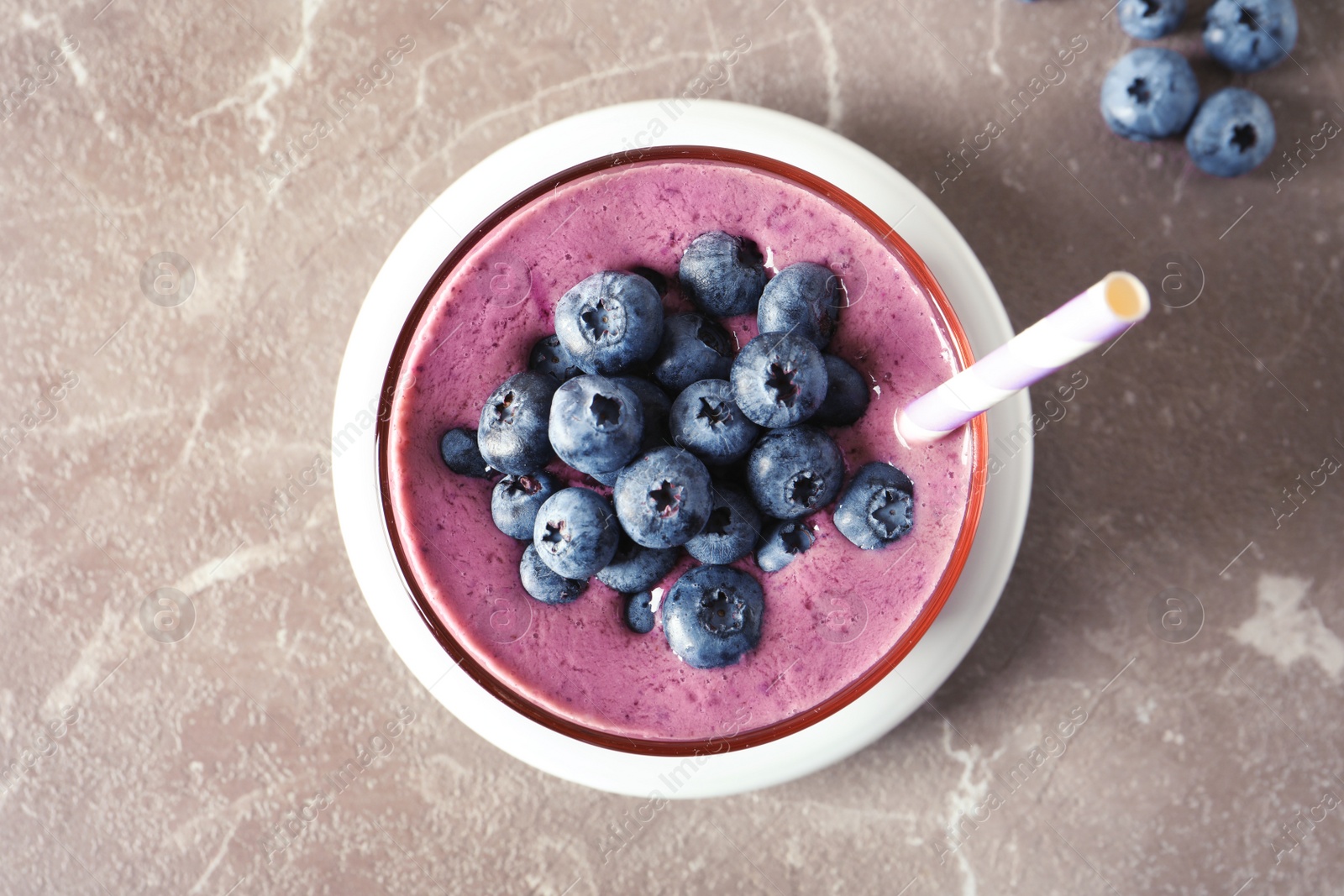 Photo of Glass with blueberry smoothie on grey background, top view