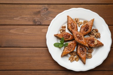 Photo of Delicious honey baklava with walnuts on wooden table, top view. Space for text