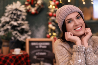 Photo of Beautiful woman in decorated cafe, space for text. Christmas celebration