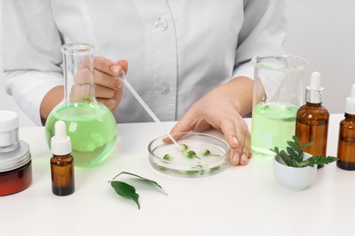 Photo of Female dermatologist creating skin care product at table, closeup