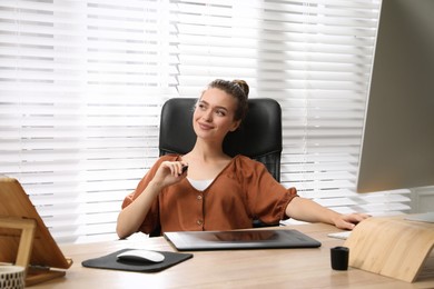 Photo of Professional retoucher working on graphic tablet at desk in office