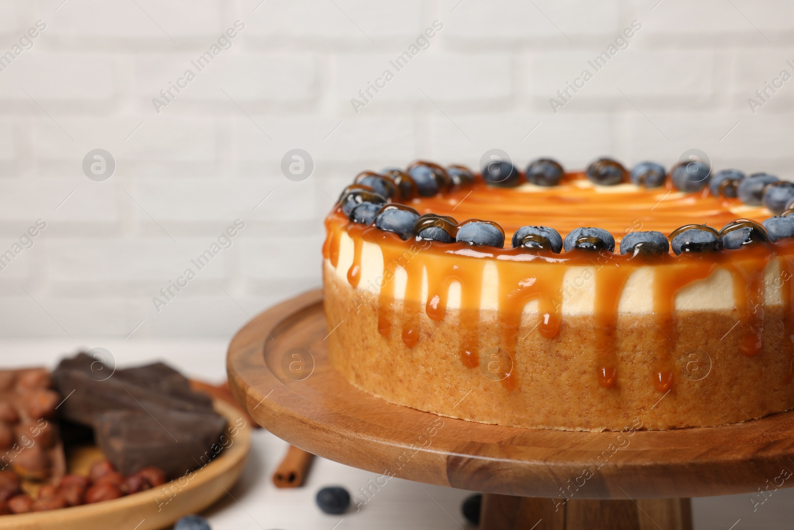 Photo of Delicious cheesecake with caramel and blueberries, closeup. Space for text