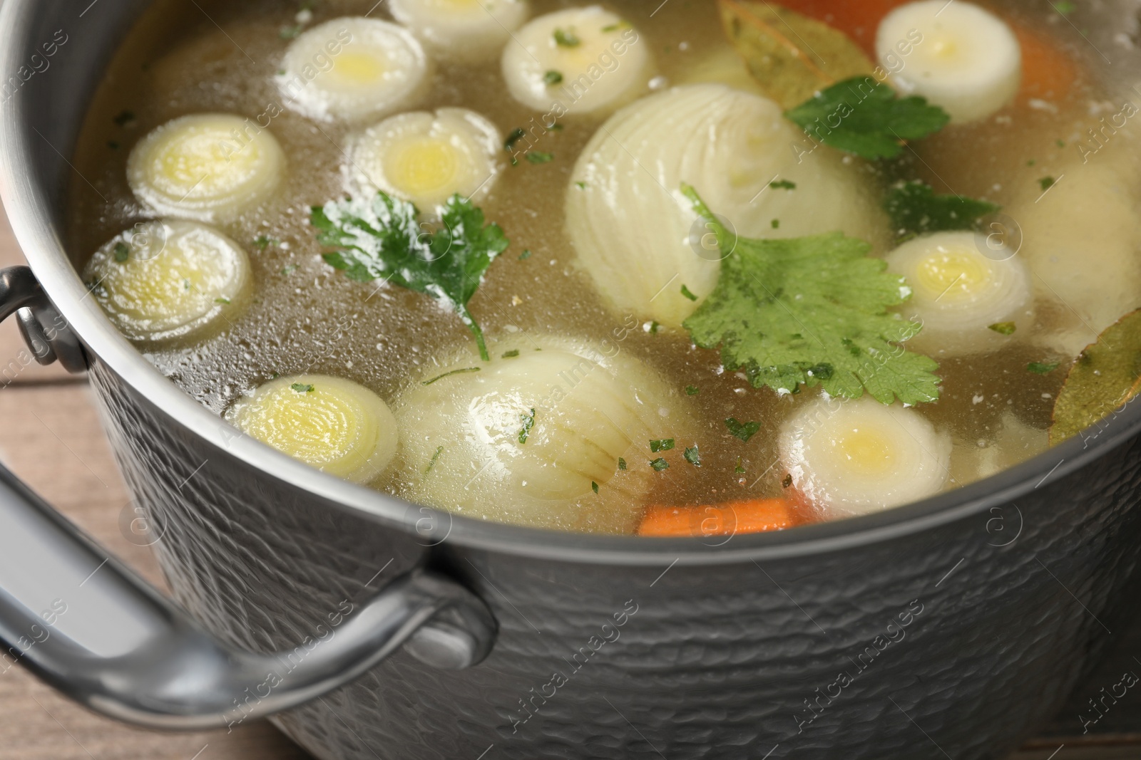 Photo of Pot with tasty bouillon on wooden table, closeup