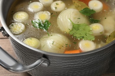 Photo of Pot with tasty bouillon on wooden table, closeup