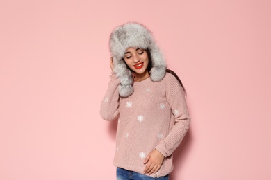 Photo of Young woman in warm sweater and hat on color background. Celebrating Christmas