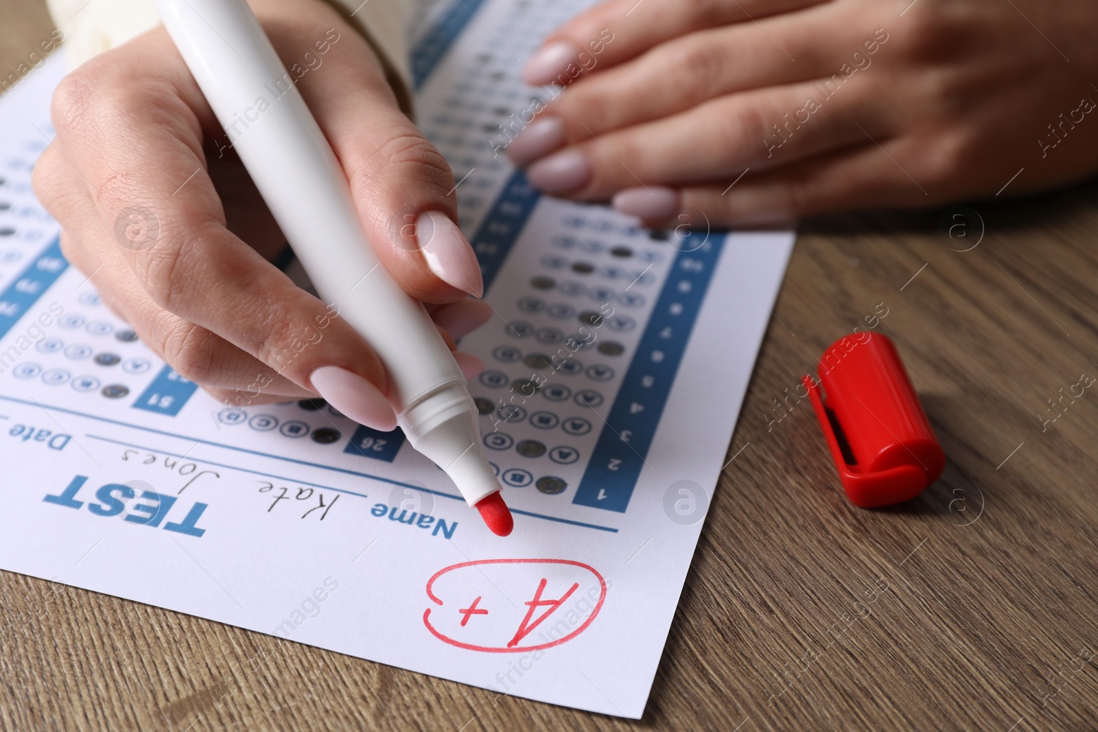 Photo of School grade. Teacher writing letter A with plus symbol on answer sheet at wooden table, closeup