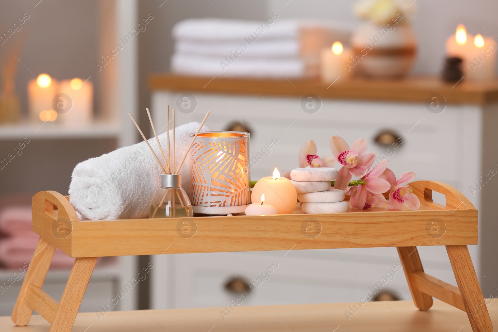 Photo of Composition with candles, flowers and stones on wooden table in spa salon