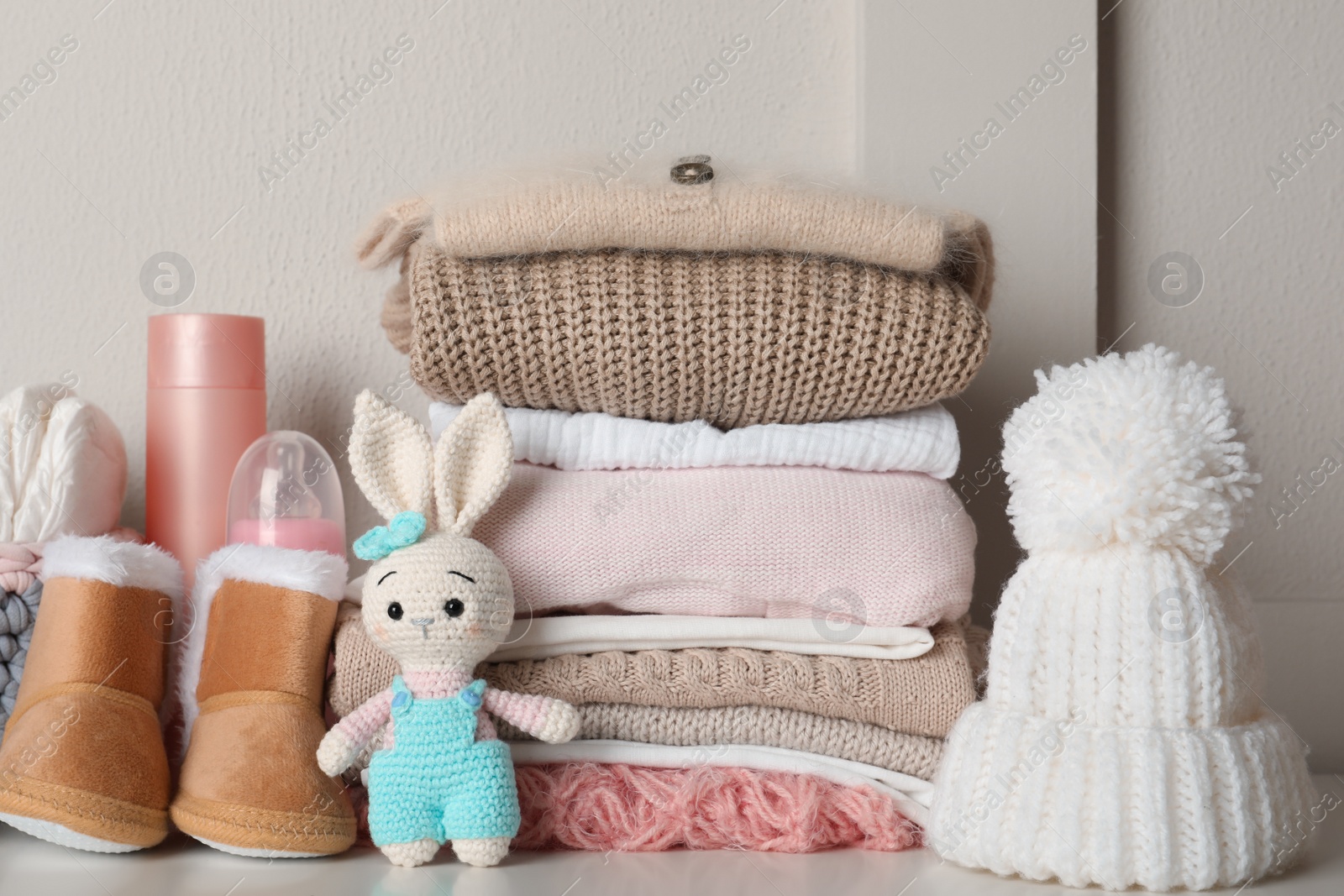 Photo of Baby clothes, toy and accessories on white table