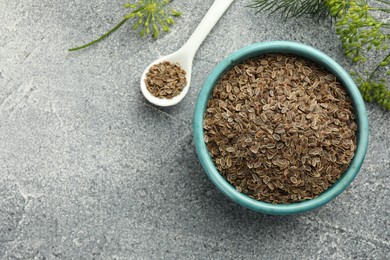 Photo of Bowl of dry seeds, spoon and fresh dill on grey table, flat lay. Space for text
