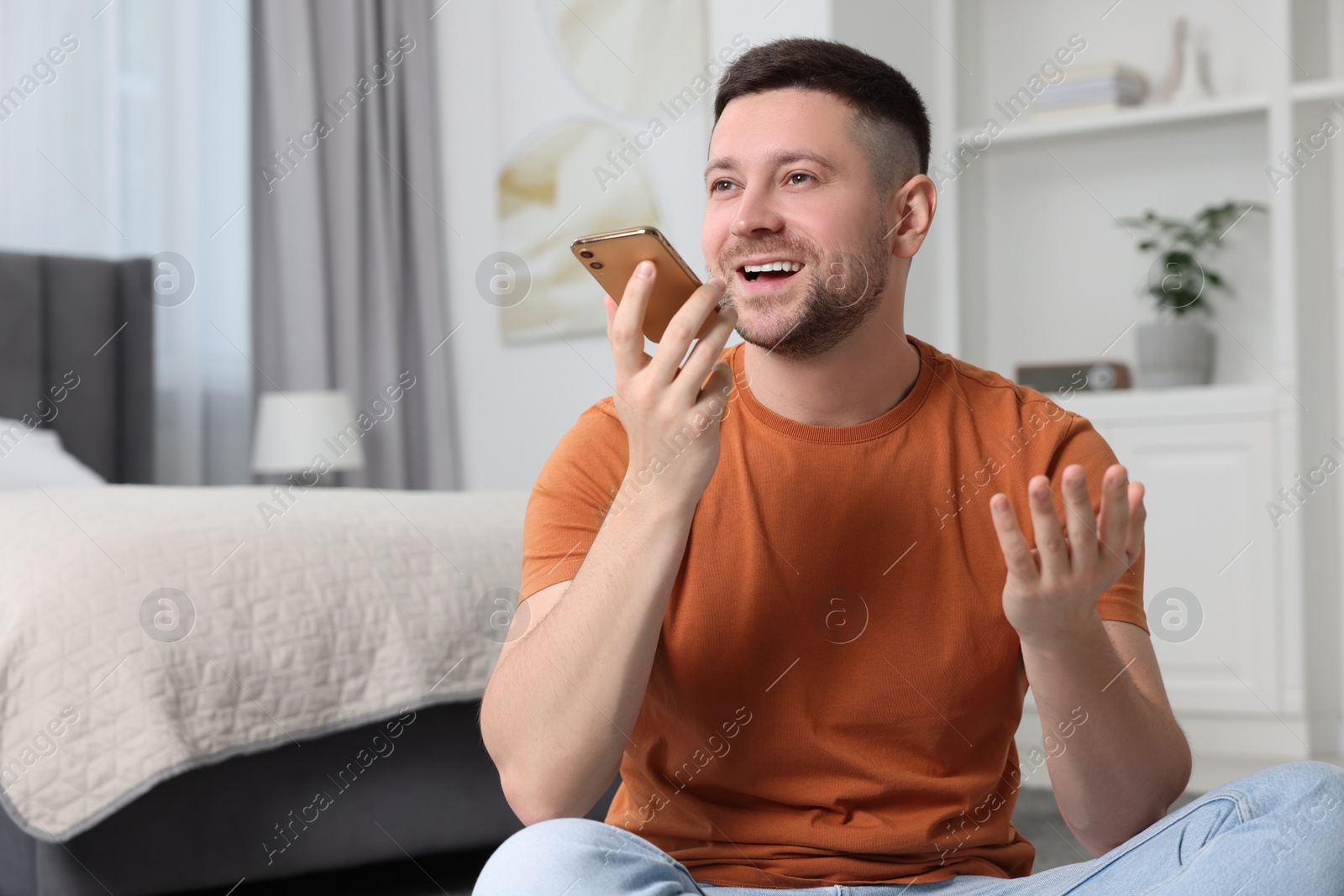 Photo of Handsome man recording voice message via smartphone at home