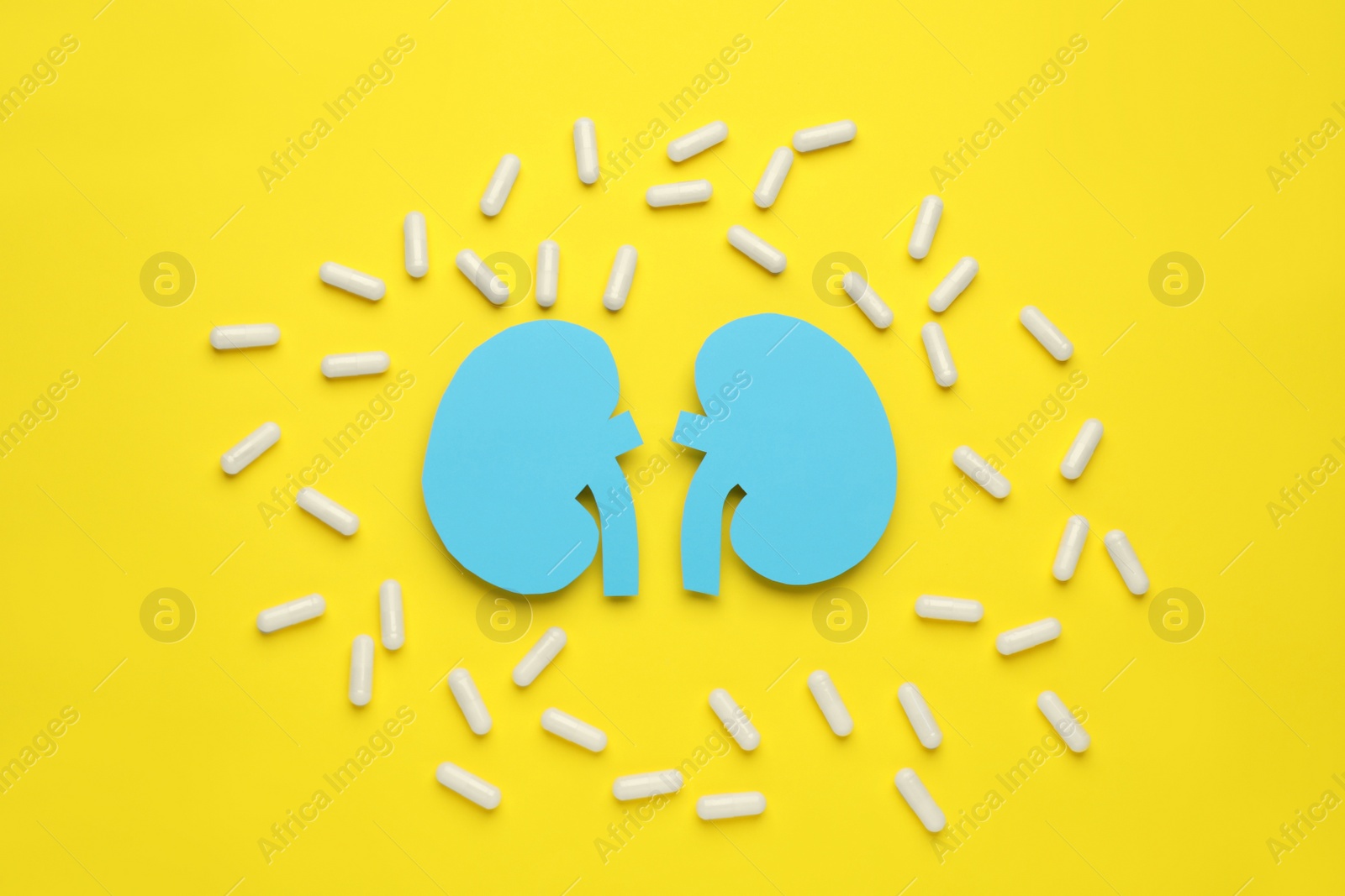 Photo of Paper cutout of kidneys and pills on yellow background, flat lay