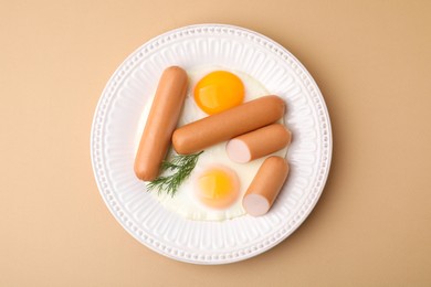 Delicious boiled sausages, fried eggs and dill on beige background, top view