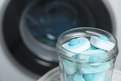 Photo of Jar with water softener tablets near washing machine, closeup. Space for text