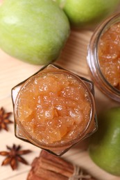 Photo of Delicious apple jam in jars, fresh fruits and spices on wooden table, flat lay