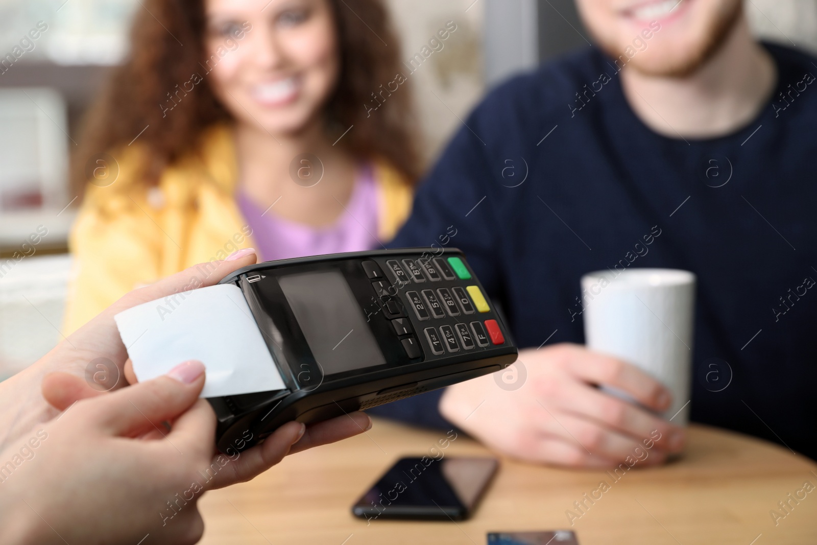 Photo of Clients using credit card machine for non cash payment in cafe, closeup
